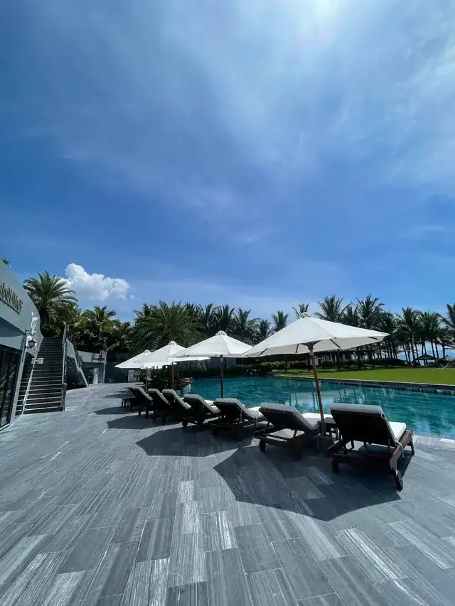 Axi Beach Lounge Cam Ranh sun loungers and umbrellas by the pool area with ocean view