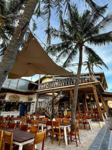 Wooden tables and loungers on the sand at sunset food court Mui Ne