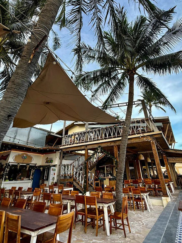 Wooden tables and loungers on the sand at sunset food court Mui Ne