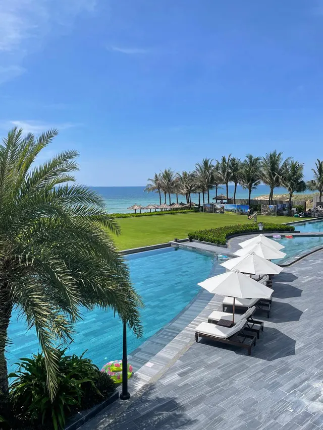 Freshwater pool surrounded by green lawn at Axi Beach Lounge Cam Ranh
