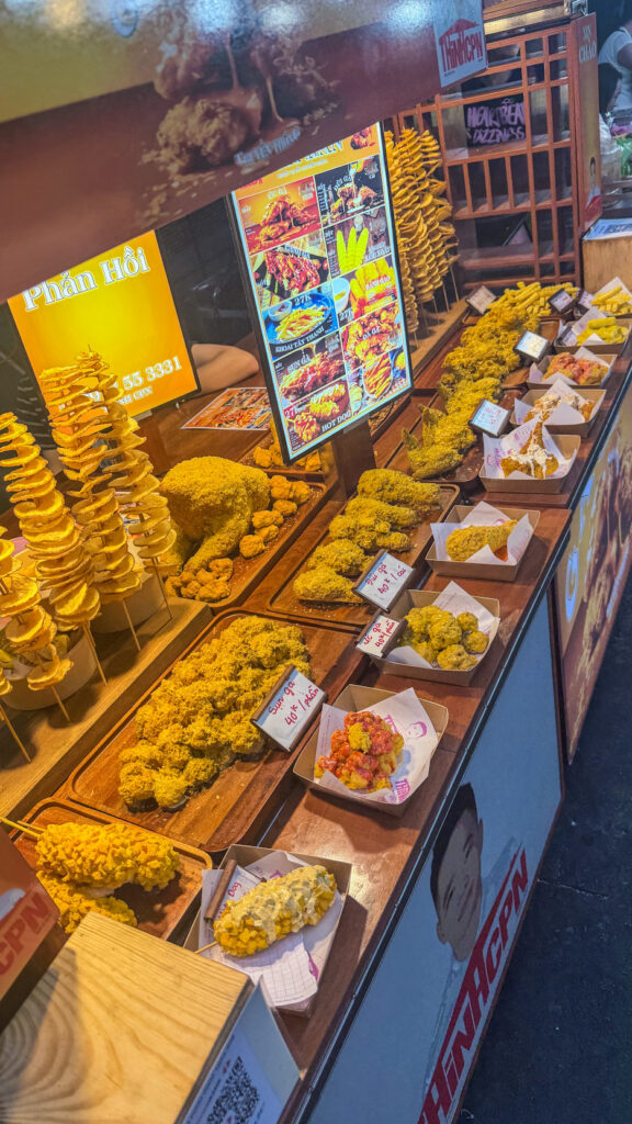Hồ Thị Kỷ street food alley with grilled chicken and vendors beside the flower market Saigon