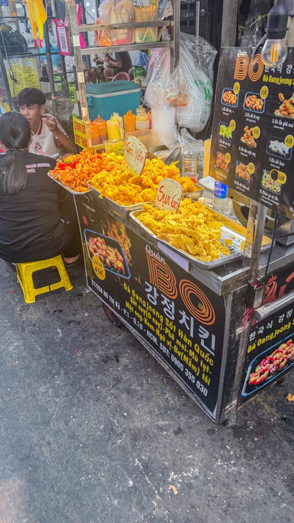 Hồ Thị Kỷ street food alley with grilled chicken and vendors beside the flower market Saigon