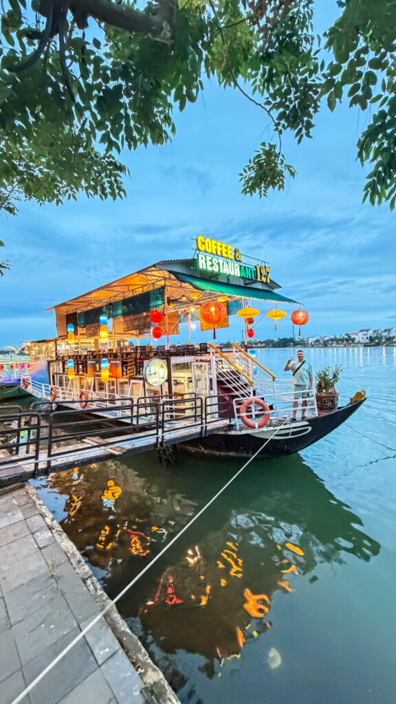 River dining with lantern boats passing by in Hoi An

