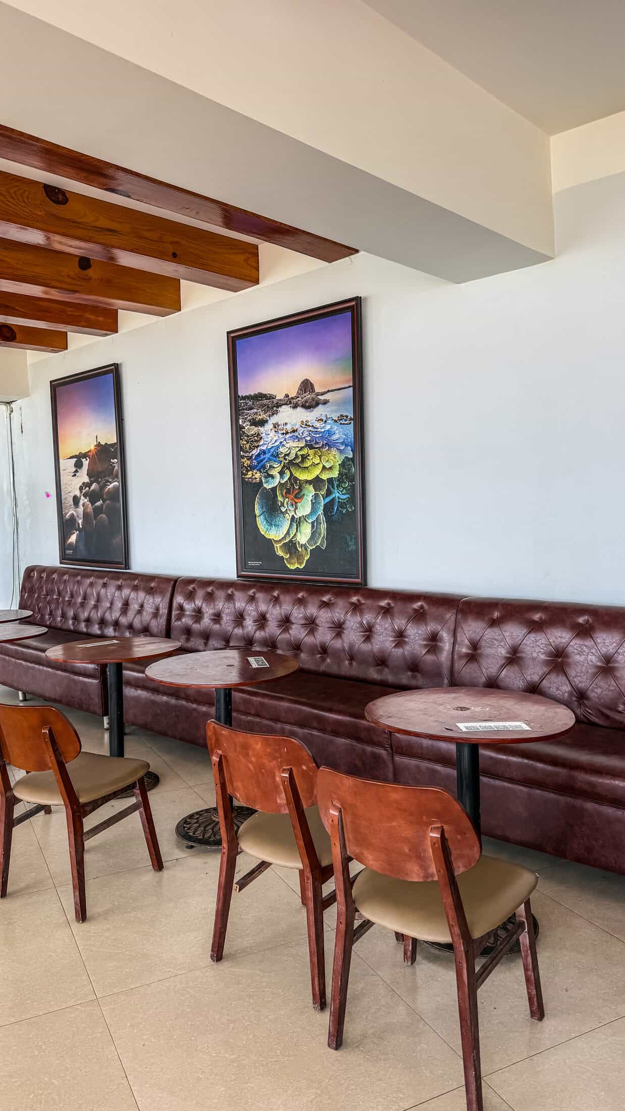 Tufted leather booth seating and framed coastal art inside Cafe Thap Nghinh Phong