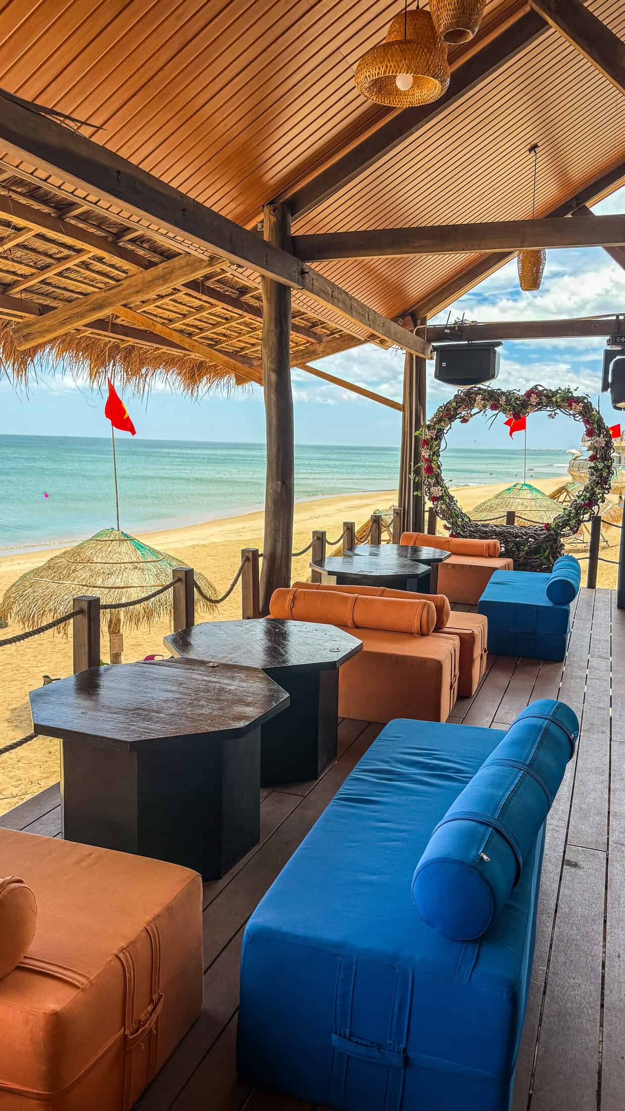 Orange and blue lounge daybeds under a thatched roof at Coffee Ayaru Nghinh Phong