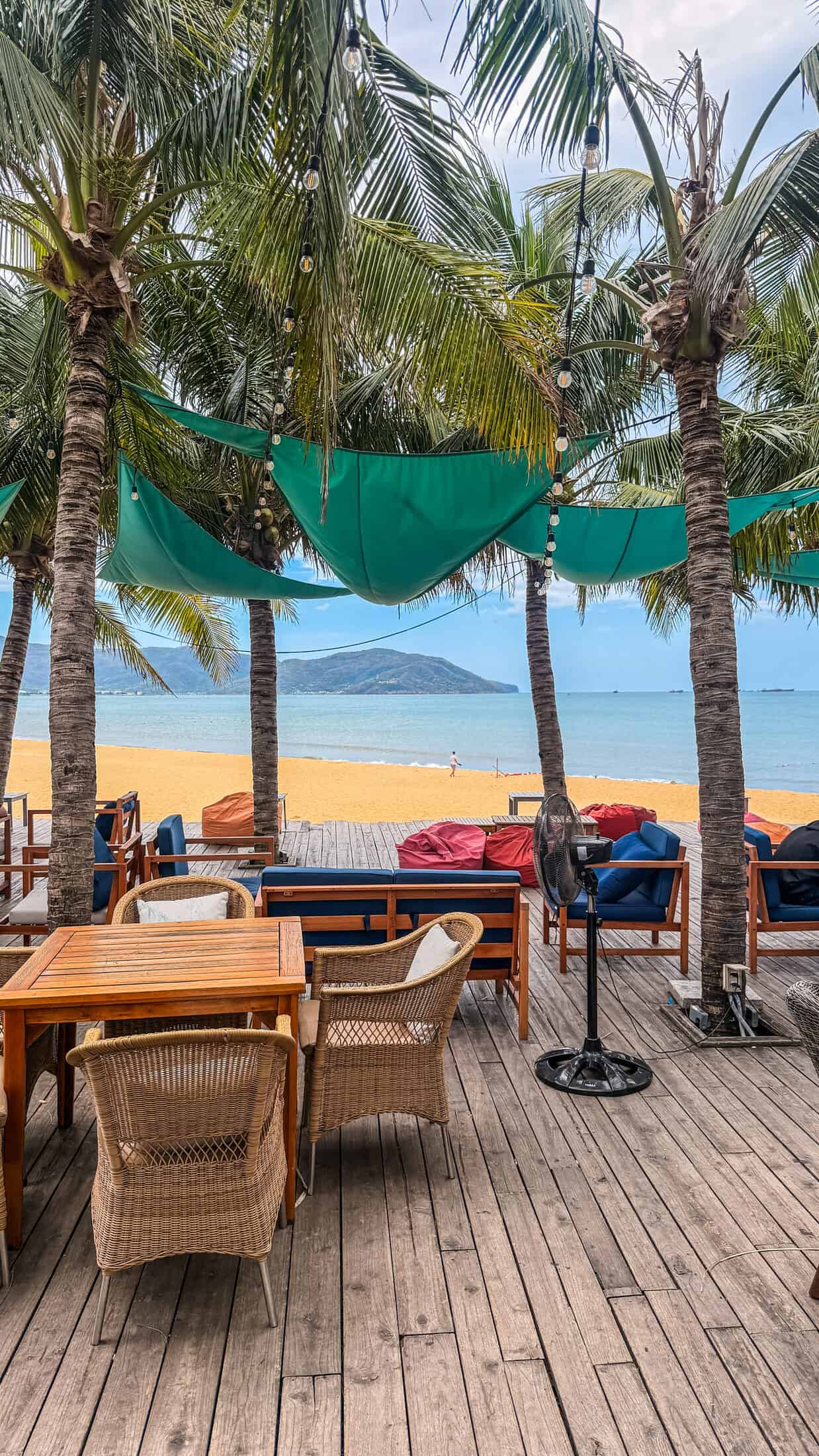 Wicker dining table under palm trees at Bốn Mùa (Four Seasons), Quy Nhon