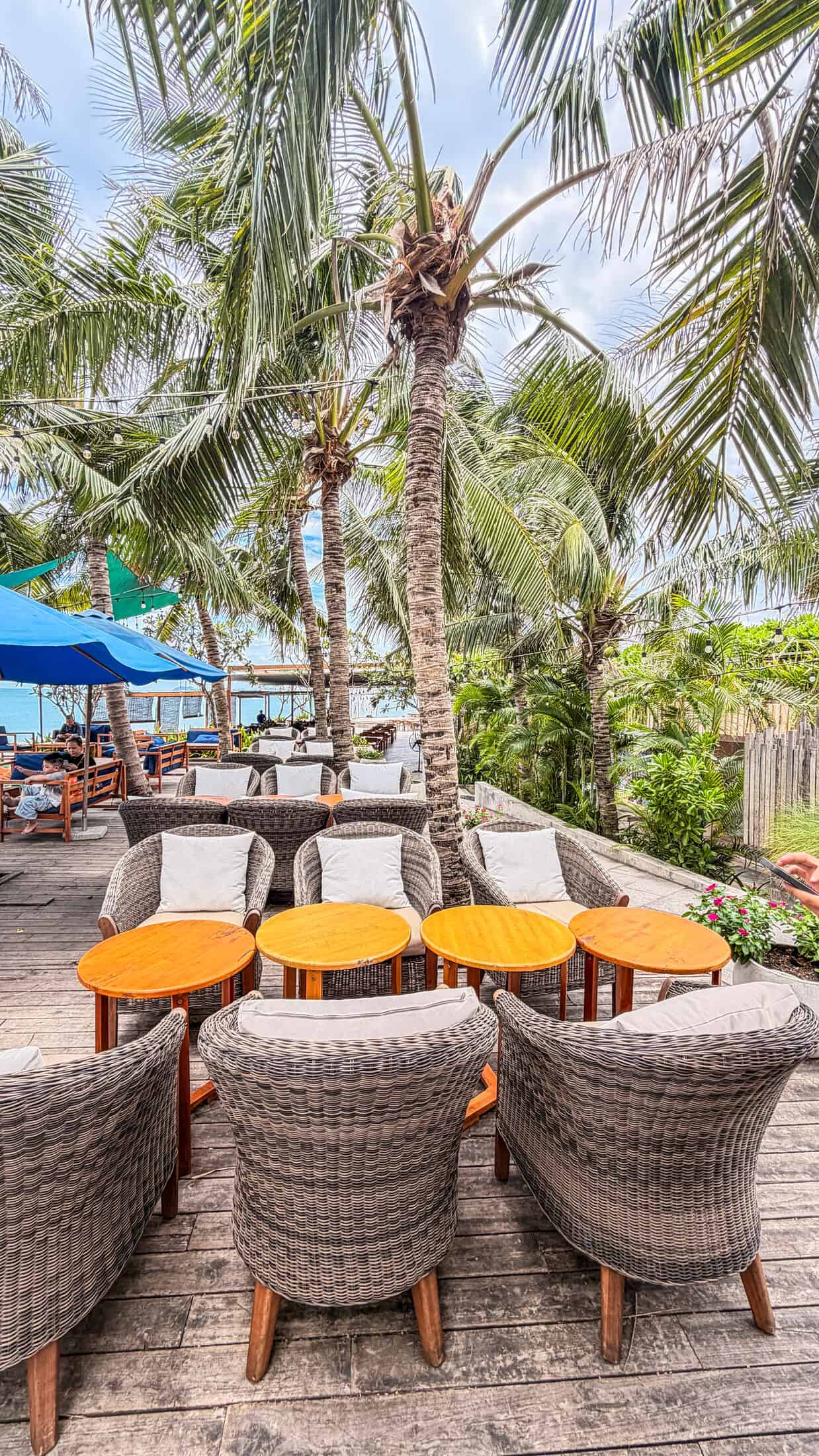Wicker lounge seating under palm trees at Bốn Mùa (Four Seasons), Quy Nhon