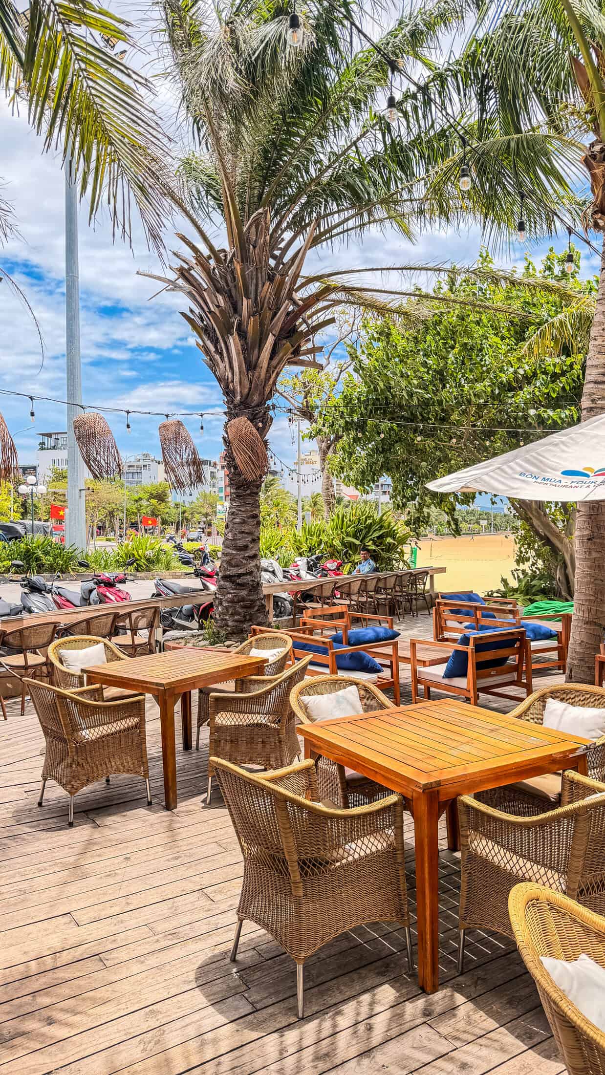Terrace seating near the road with the restaurant's branded umbrella at Bốn Mùa (Four Seasons), Quy Nhon