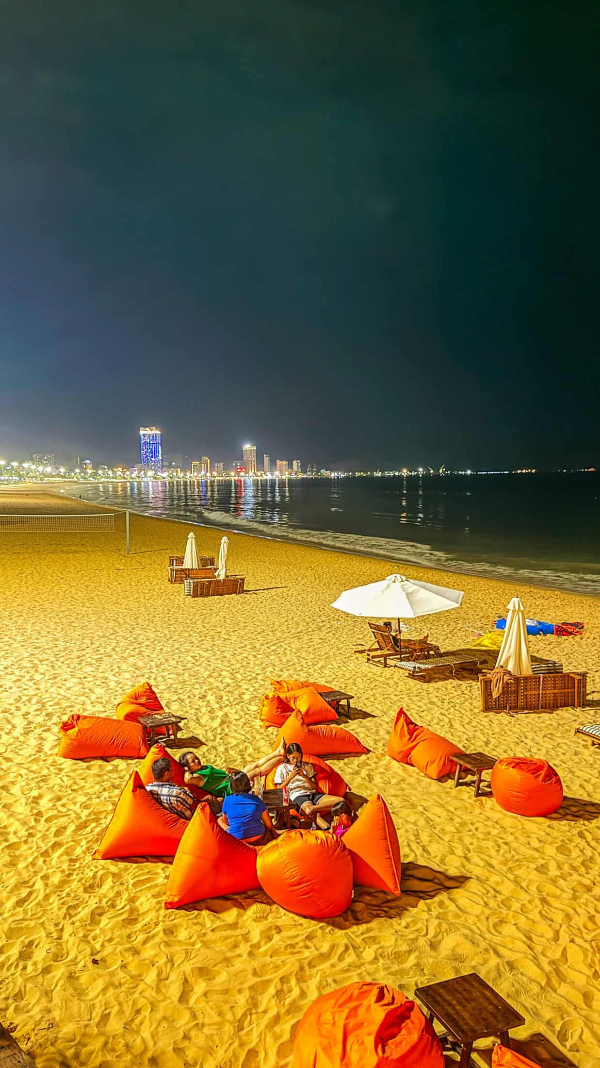 Neon sign and thatched bar at night at Kifa Beach, Quy Nhon