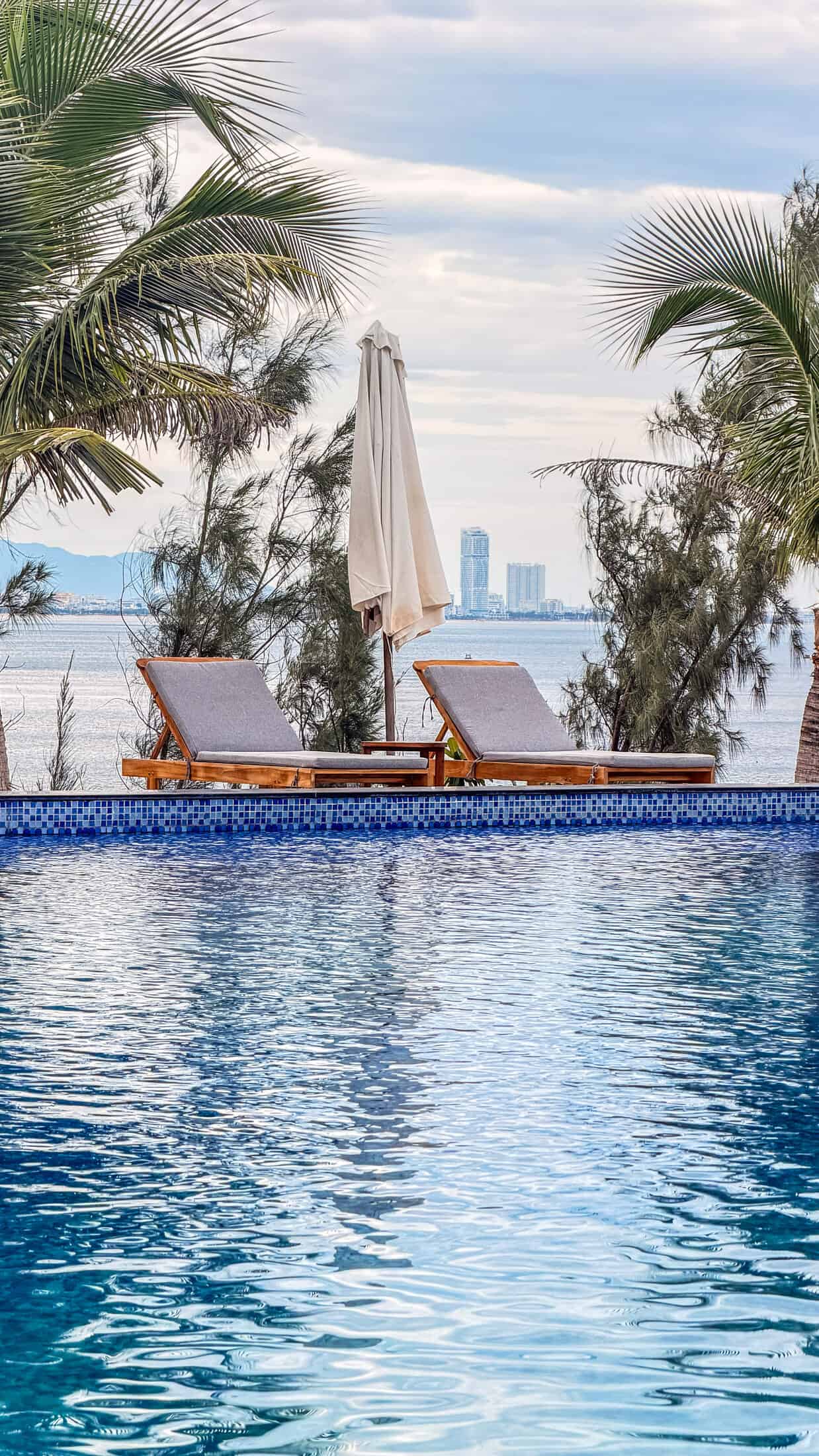 Poolside loungers with a view of the city skyline across the bay at La Costa Resort, Quy Nhon