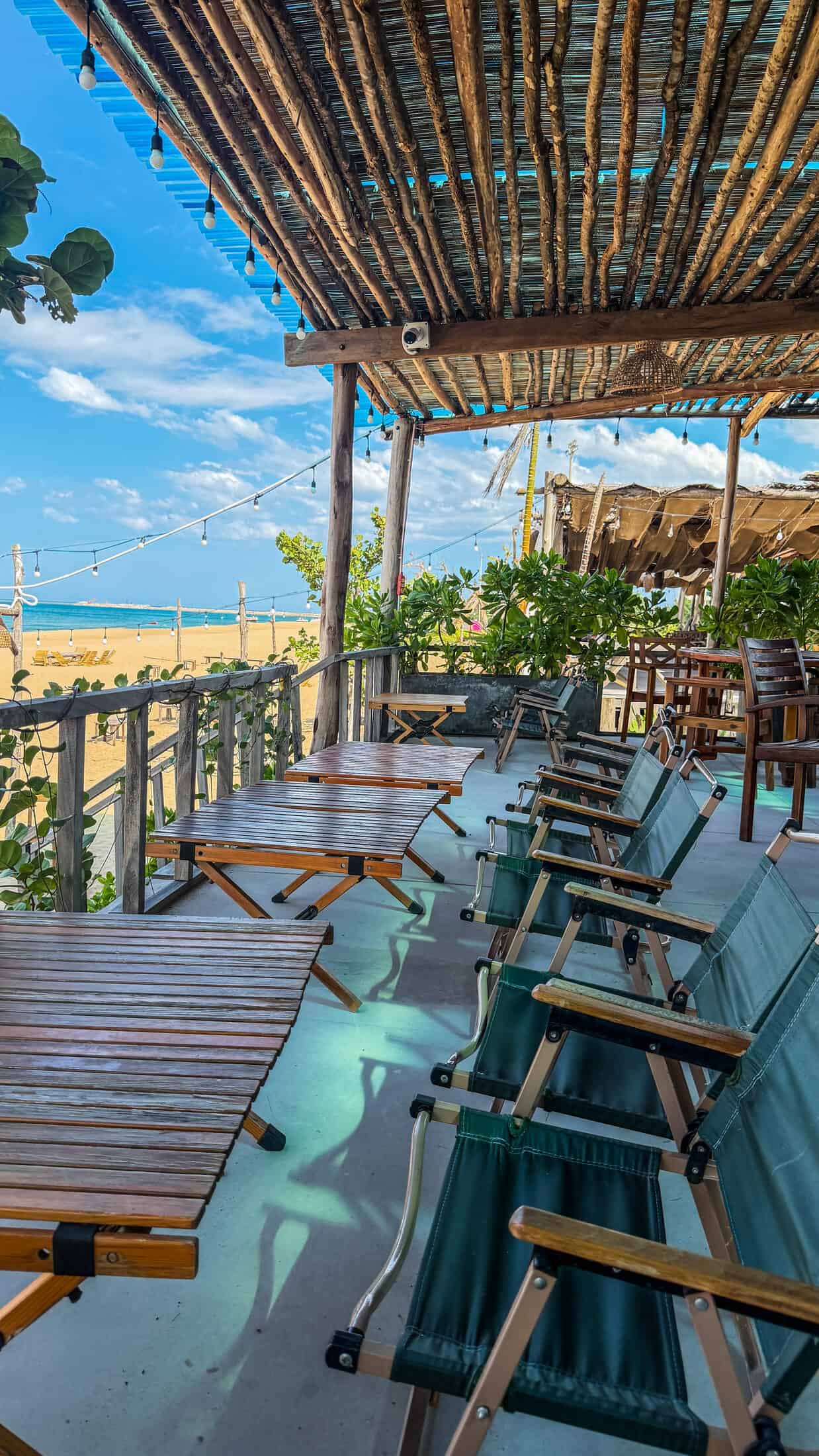 Low camping-style chairs and string lights overlooking the beach at Lumiere Beach Bistro