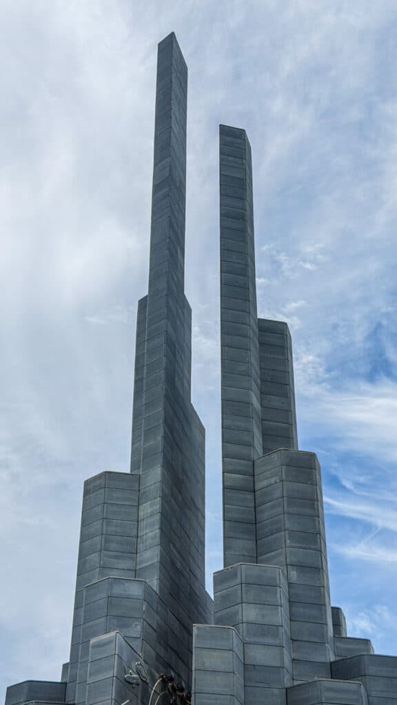 Looking straight up at the twin stone spires of Nghinh Phong Tower against the sky