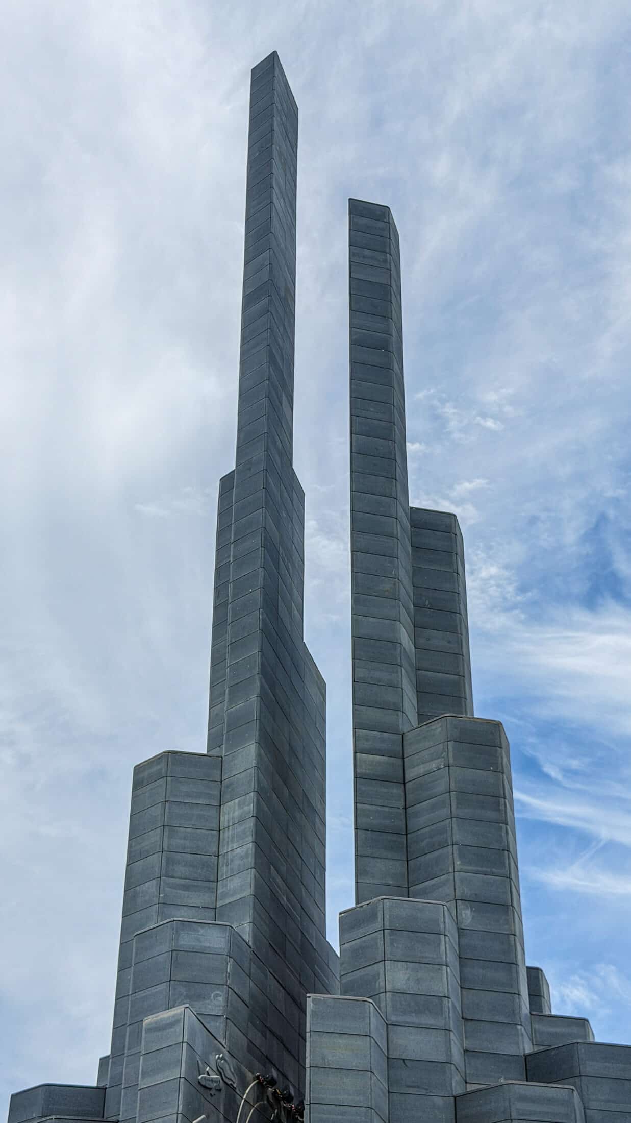 Looking straight up at the twin stone spires of Nghinh Phong Tower against the sky