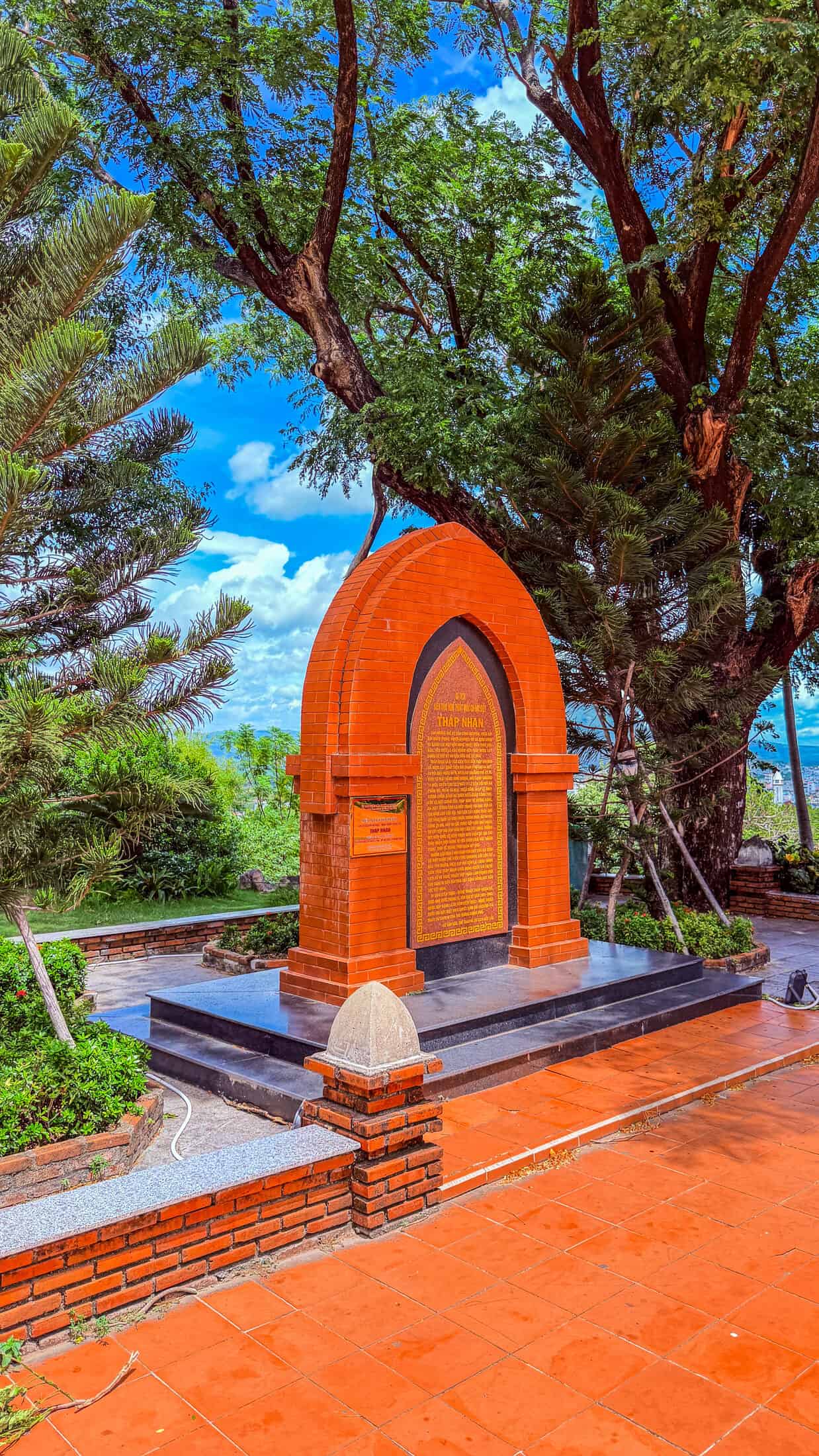 Arched brick memorial marker with inscription plaque at the entrance to Nhan Tower