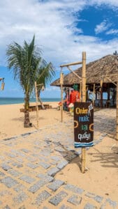 Thatched beach hut with order sign and palm tree at Ocean Kite Coffee, Tuy Hoa