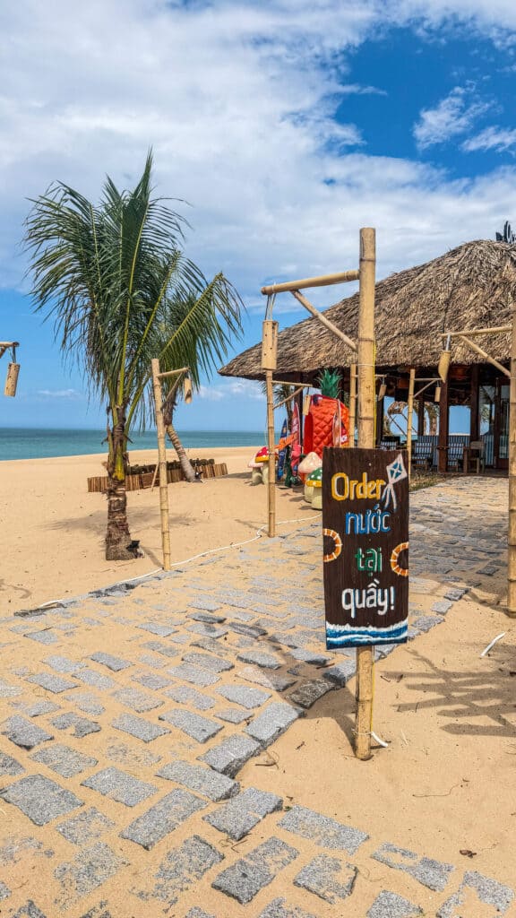 Thatched beach hut with order sign and palm tree at Ocean Kite Coffee, Tuy Hoa