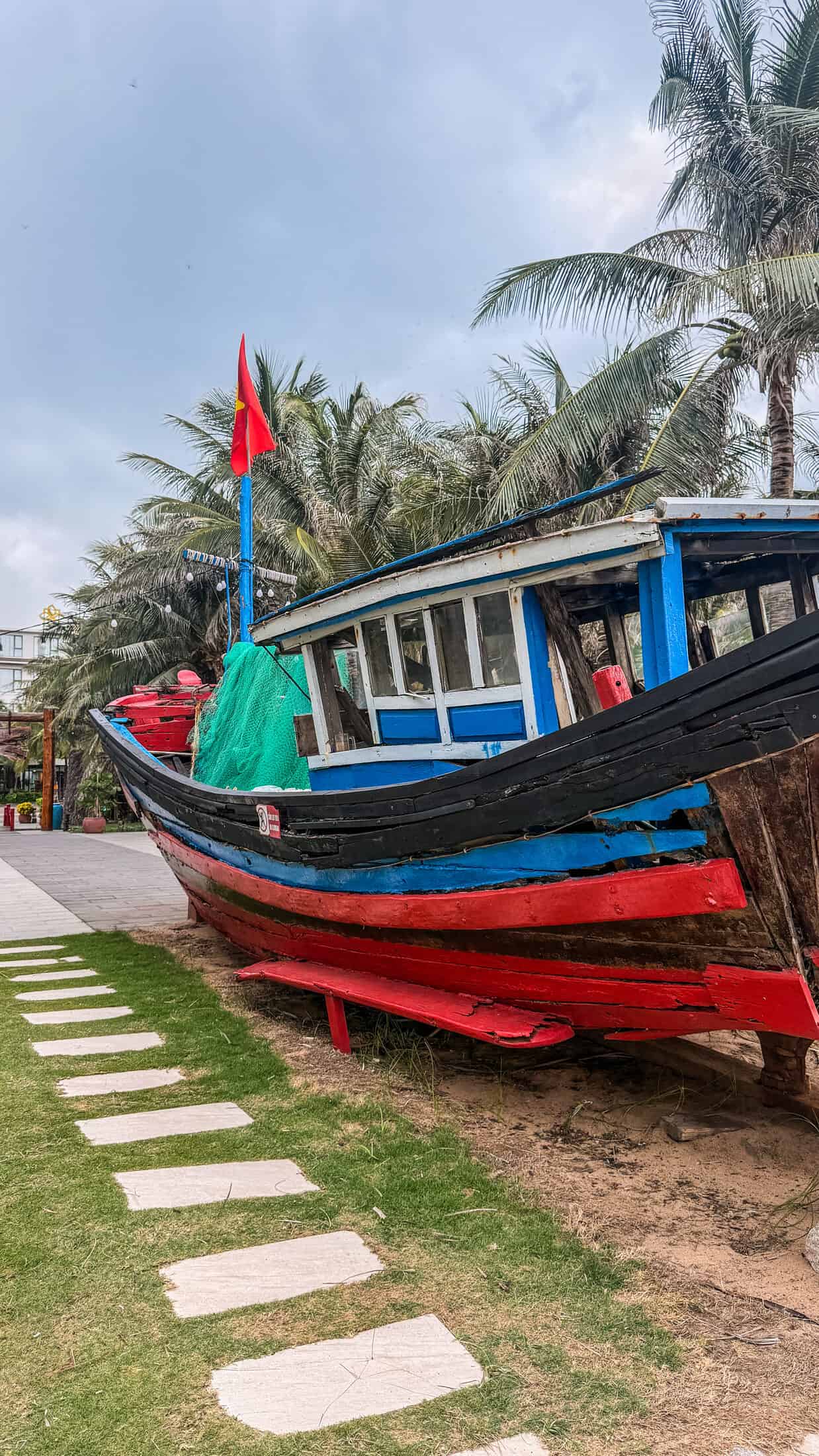 Traditional Vietnamese fishing boat displayed on the lawn at Sala TuyHoa Beach Club