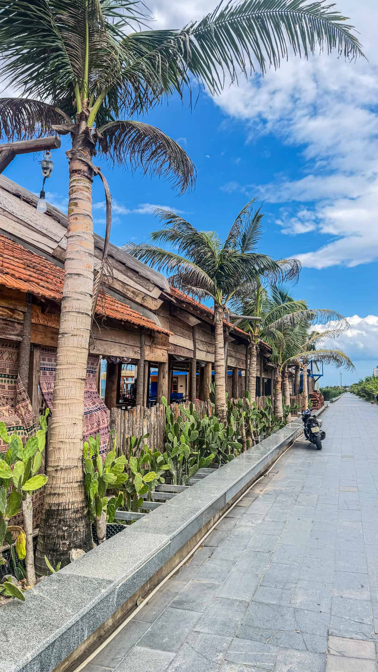Row of wooden beachfront pavilions with terracotta roofs at Tiqua Land, Tuy Hoa