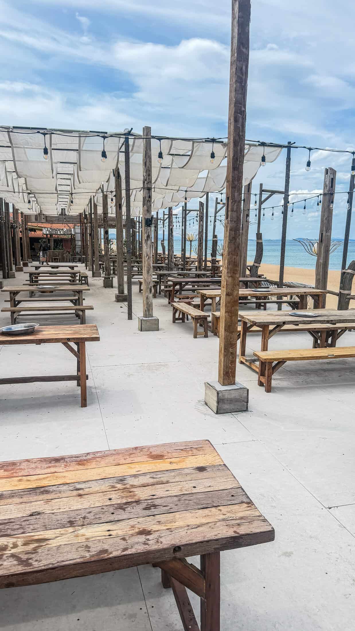 Open-air picnic tables under canvas sail shading at Tiqua Land beach club