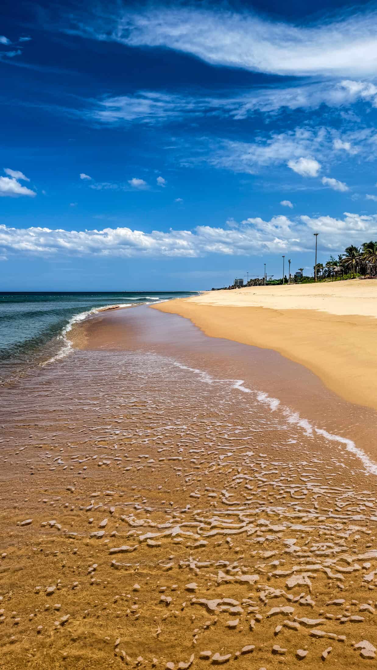Gentle waves washing over textured wet sand at the water's edge in Tuy Hoa