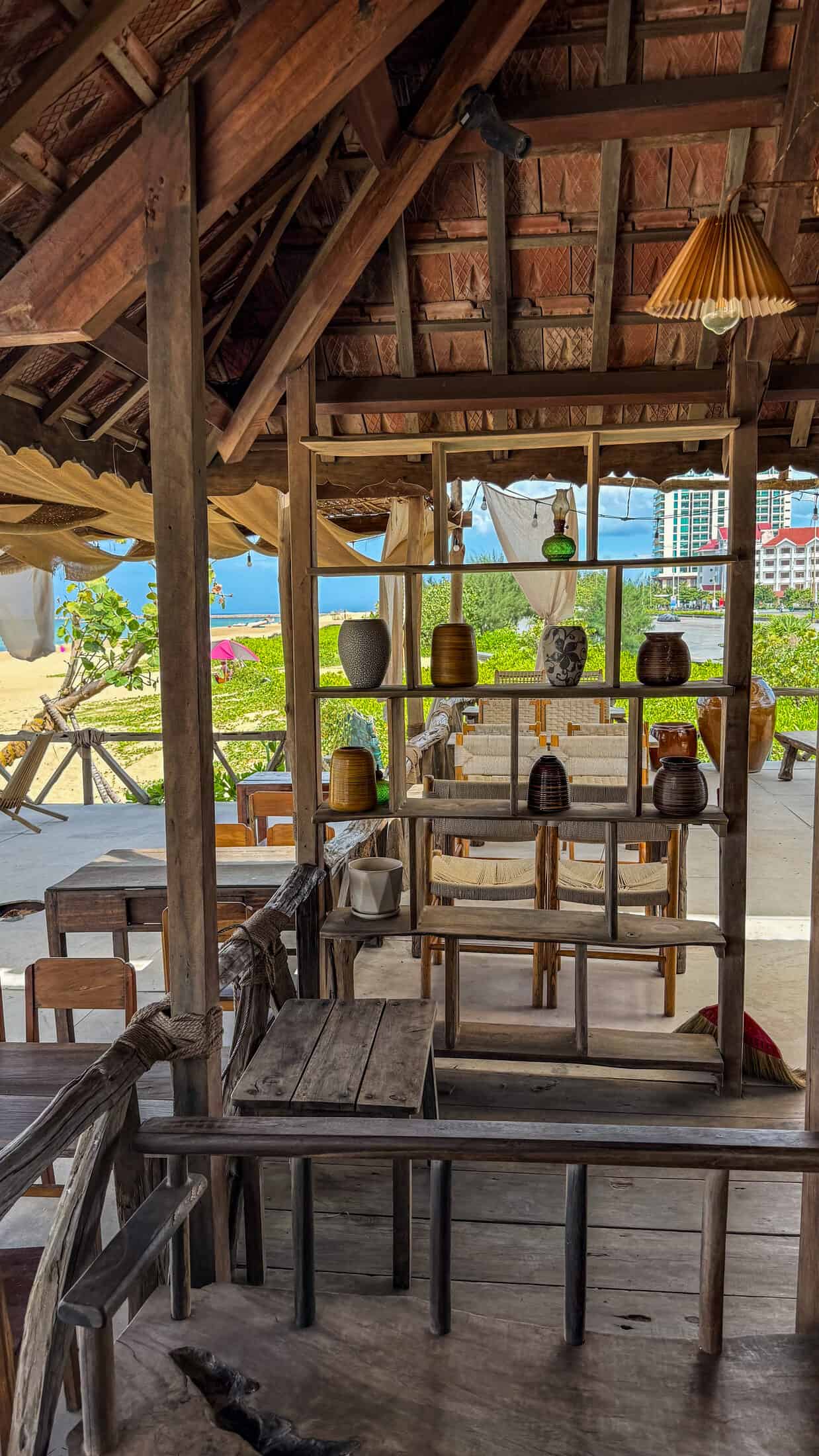 Thatched-roof seating area with ceramic decor at Wild Wind Beach Coffee, city skyline behind